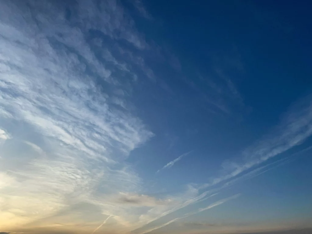 Ciel bleu nuageux illuminé par la lumière du soleil couchant.