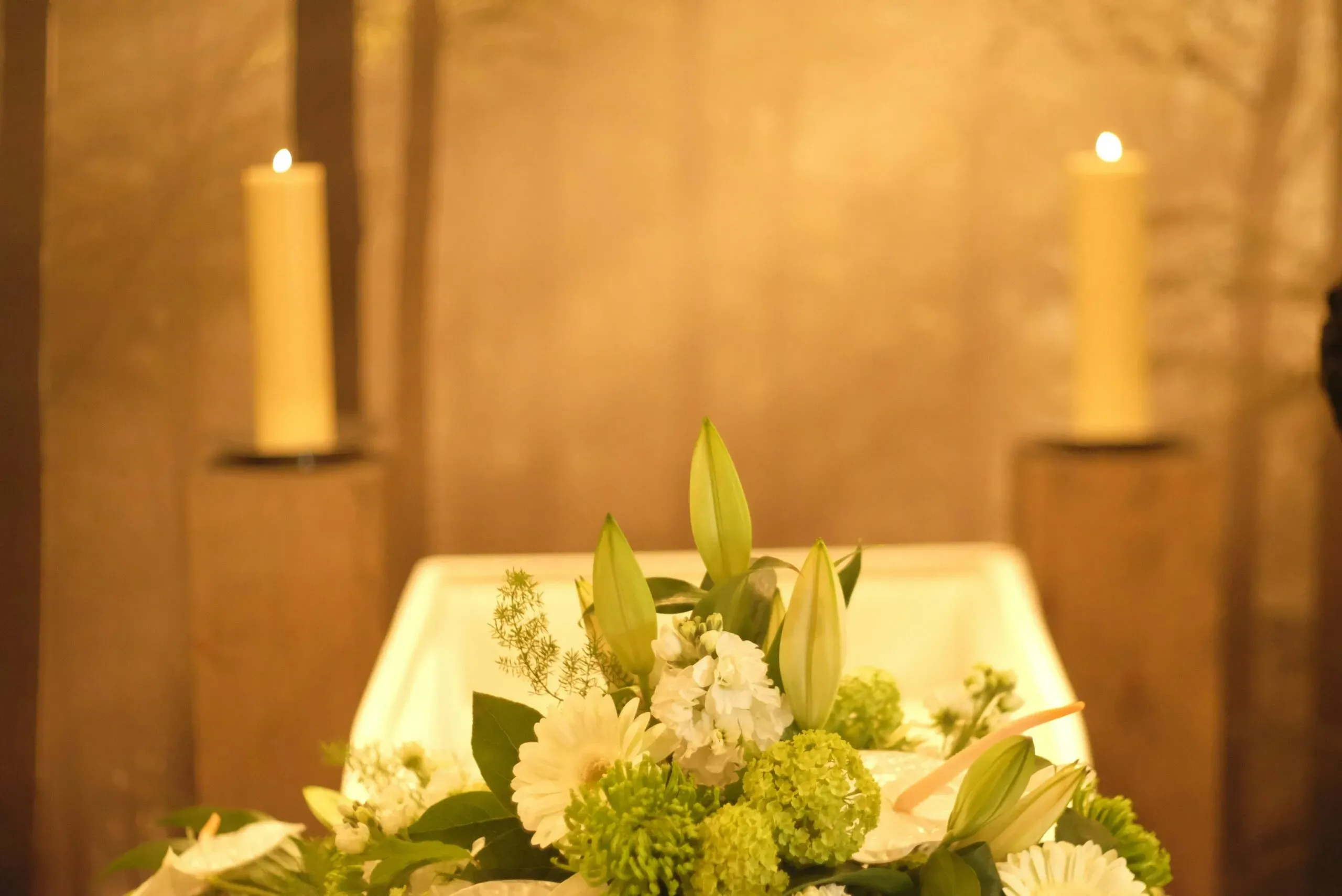 Composition de fleurs blanches et bougies allumées pour une cérémonie.