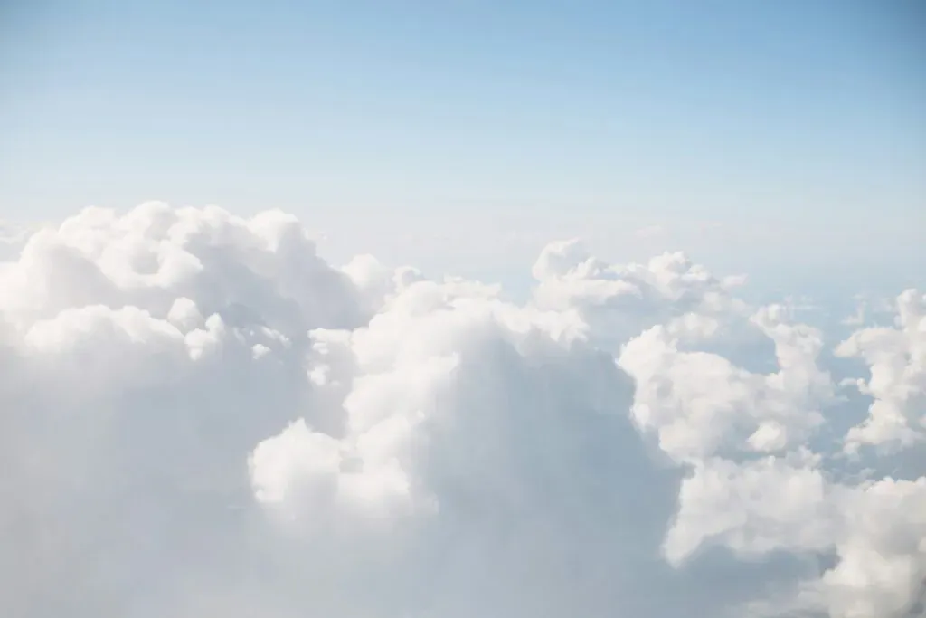 Nuages blancs cotonneux sur fond de ciel bleu clair apaisant.